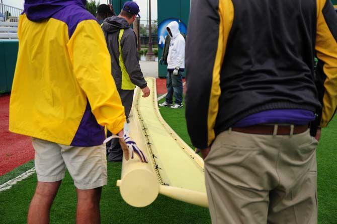 Members of LSU Athletics Facilities attempt to pick up the fallen left-field foul pole in Alex Box Stadium on Monday, April 27, 2015 after a severe thunderstorm passed through Baton Rouge.