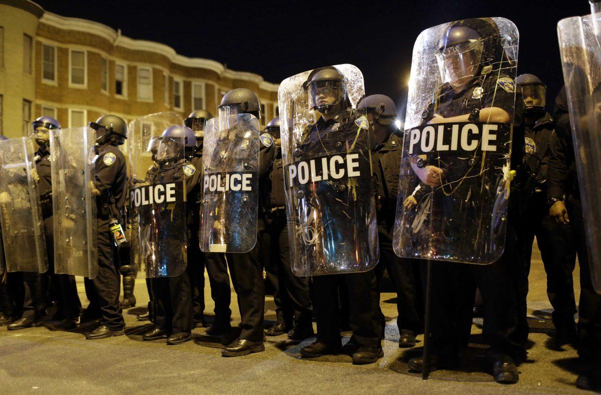 Police stand in formation as a curfew approaches, Tuesday, April 28, 2015, in Baltimore, a day after unrest that occurred following Freddie Gray's funeral. (AP Photo/Patrick Semansky)