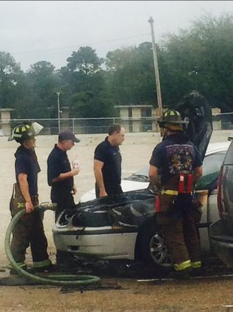 Firefighters stand around a vehicle that caught fire in the gravel commuter lot off of Skip Bertman Dr. on Tuesday morning.&#160;