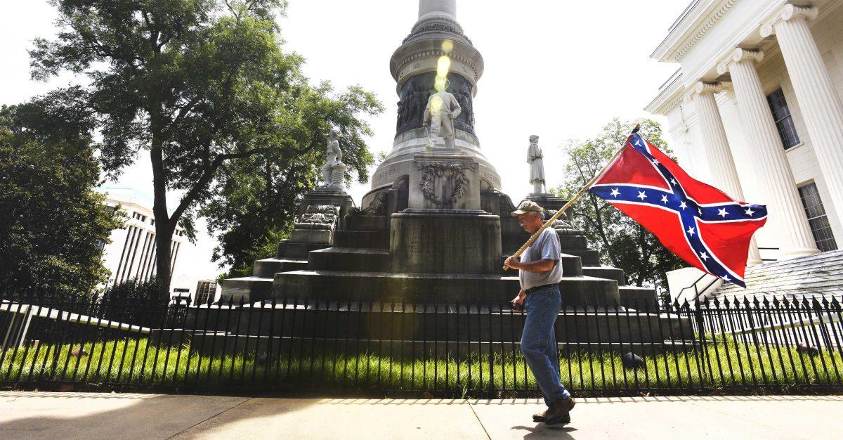 Mike Williams, adjutant for the Sons of Confederate Veterans in the state of Alabama, carries a confederate flag past the Confederate Memorial on the state Capitol grounds in Montgomery, Ala, after four flags were removed from the memorial on Wednesday, June 24, 2015. (Mickey Welsh/The Montgomery Advertiser via AP) NO SALES; MANDATORY CREDIT