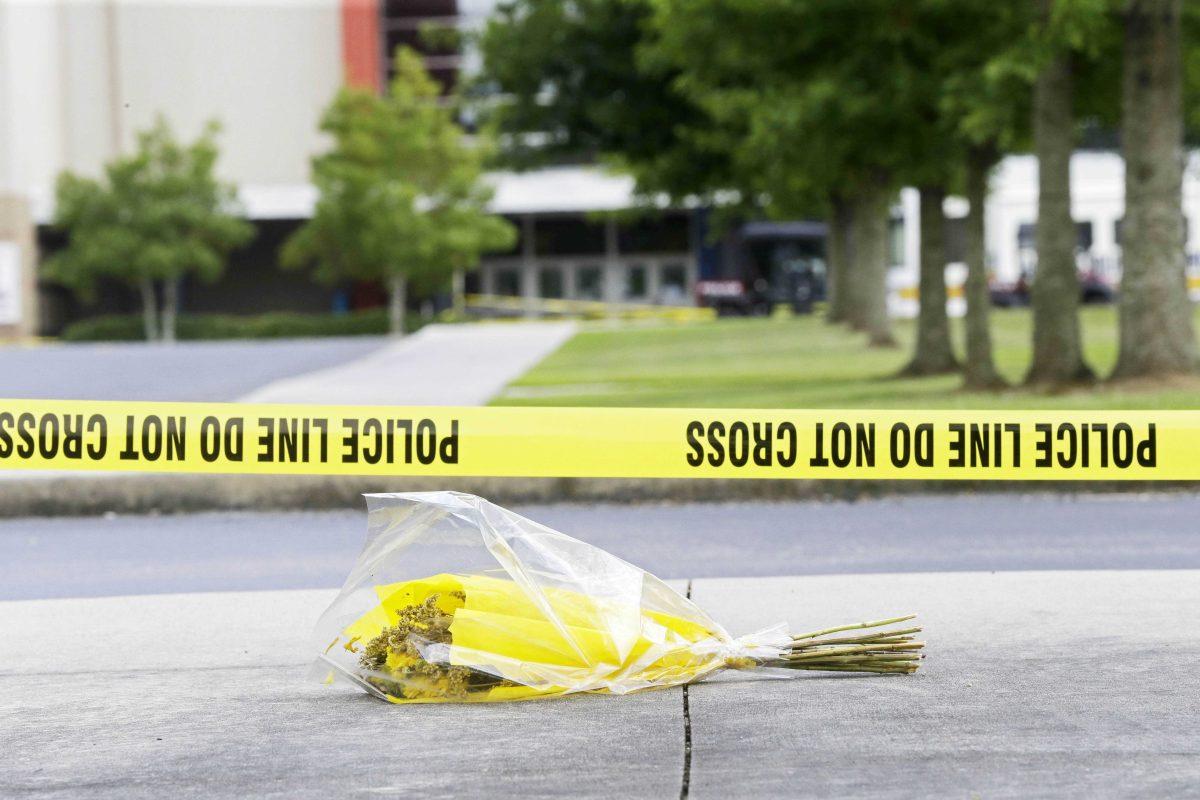 A bouquet of flowers lies net crime scene tape in the parking lot outside The Grand 16 movie theater in Lafayette, La., Sunday, July 26, 2015, Sunday, July 26, 2015, in Lafayette, La. John Russell Houser stood up about 20 minutes into Thursday night's showing of "Trainwreck" and fired on the audience with a semi-automatic handgun. (AP Photo/Gerald Herbert)