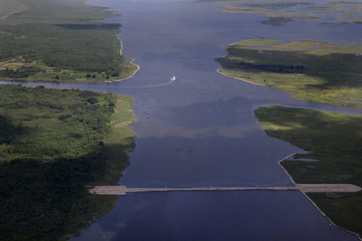 In this aerial photo made during a flight provided by the National Wildlife Federation and Southern Wings, a shrimp boat travels behind a rock dam built by the U.S. Army Corps of Engineers after Hurricane Katrina, in the Mississippi River Gulf Outlet (MRGO) in St. Bernard Parish, La., Monday, Aug. 10, 2015. The MRGO, originally built by the Corps, carried a storm surge from Katrina straight into the New Orleans area causing devastating flooding in the Parish. (AP Photo/Gerald Herbert)