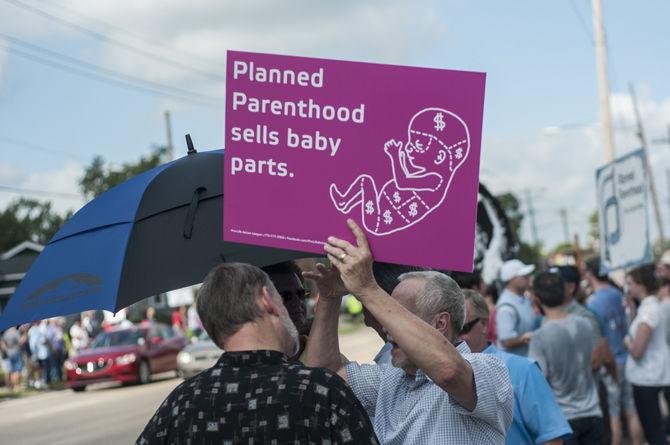 Protesters hold signs outside the planned parenthood health center on Saturday, Aug. 22, 2015 on Government Street.