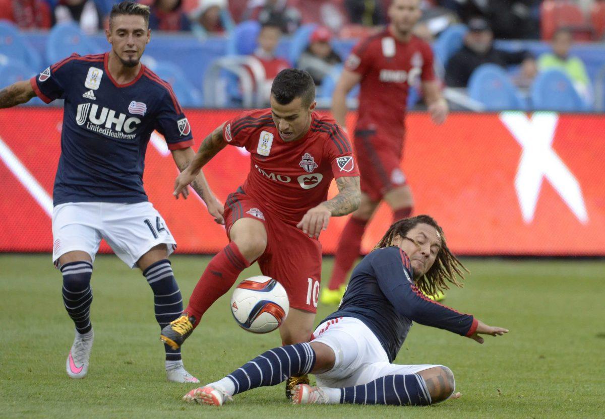 Toronto FC's Sebastian Giovinco, center, works the ball around New England Revolution's Jermaine Jones, right, during the first half of MLS soccer action on Sunday, Sept. 13, 2015, in Toronto. (Jon Blacker/The Canadian Press via AP)