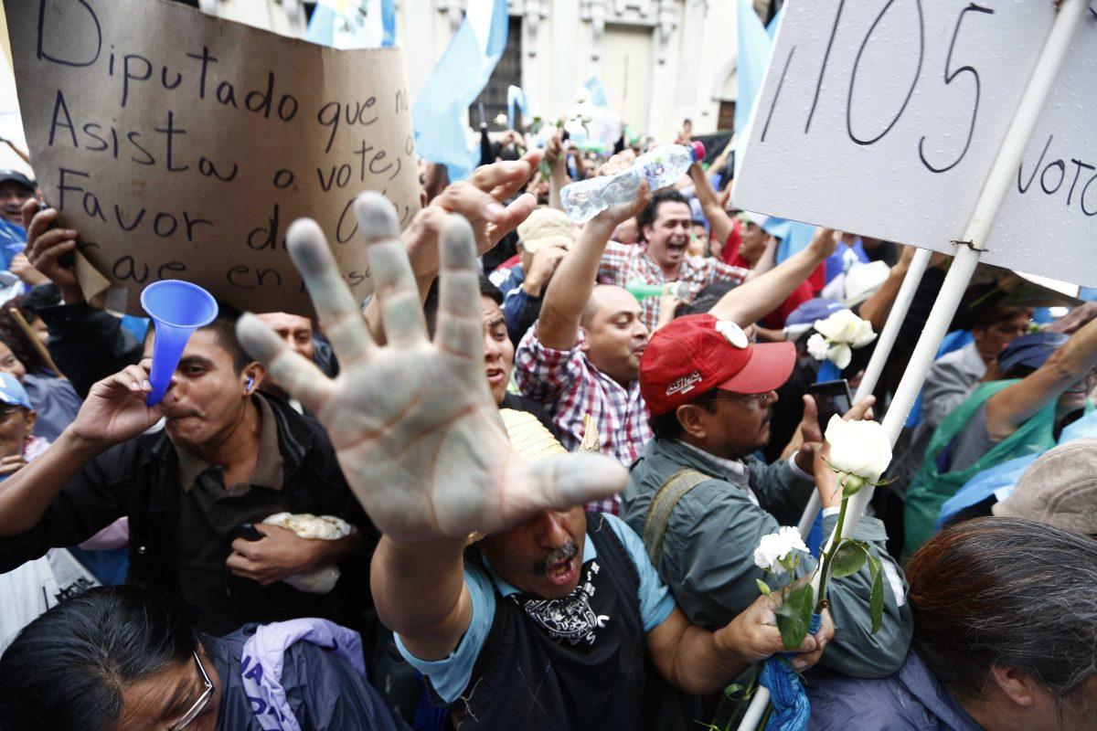 Demonstrators react in jubilation in front of the Guatemalan Congress building the as they hear the news that Congress has voted to withdraw President Otto Perez Molina's immunity from prosecution, in Guatemala City, Tuesday, Sep. 1, 2015. Perez Molina's government has been beset by a series of corruption cases, but until now he has been immune to prosecution as president. (AP Photo Moises Castillo)