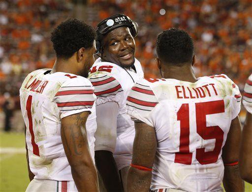 Ohio State quarterback Cardale Jones, center, talks with teammates Ezekiel Elliott (15) and Braxton Miller, left, during the second half of an NCAA college football game in Blacksburg, Va., Monday, Sept. 7, 2015. Ohio State won 42-24. (AP Photo/Steve Helber)