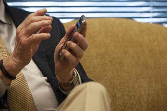 Secretary of State Tom Schedler holds up his personal iPhone as he explains Geauxvote.com on Friday, Sept. 25, 2015, in his office.