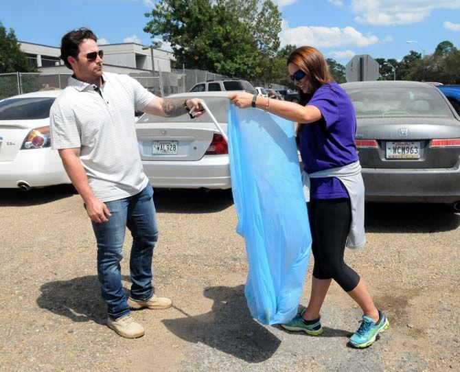 Project engineer Carson Narcomey and marketing and proposal coordinator Erica Hinds work together to pick up trash for the Lemoine Company wellness and service project Friday September 18, 2015 near the UREC.