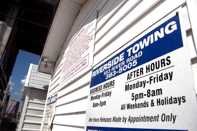 Business hours and prices are clearly marked on the sign at Riverside Towing on River Road.