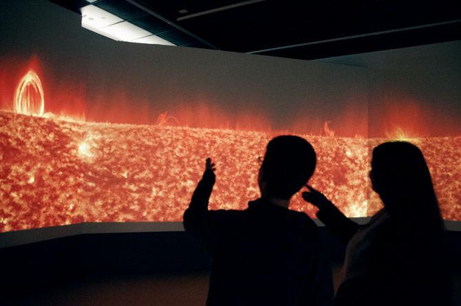 Audience engagement and public relations manager Douglas Kennedy and museum guide Mina Major discuss "Solarium," an installation by NASA's Solar Dynamics Observatory that simulates the look and sound of the surface of our sun in the new "Sun Light/Star Light: Contemplations on the Solar Orb" exhibit at the Louisiana Art and Science Museum.