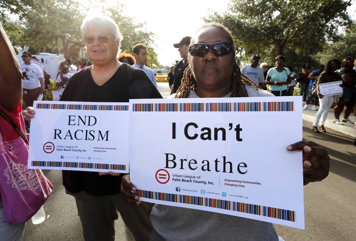 Attendees hold signs at a 'rally for answers' on Thursday, Oct. 22, 2015, in Palm Beach Gardens, Fla., in support of Corey Jones, who was fatally shot by a South Florida police officer. (AP Photo/Joe Skipper)