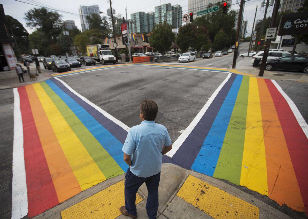 A pedestrian waits to cross a rainbow painted crosswalk in midtown to commemorate this weekend's annual Atlanta Pride parade Friday, Oct. 9, 2015, in Atlanta. The pride parade is one of the oldest in the country and the largest pride event in the southeast. (AP Photo/David Goldman)