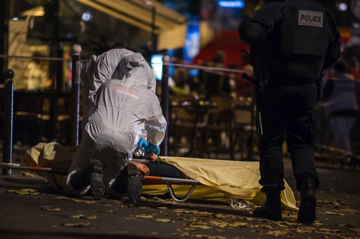 Investigating police officers inspect the lifeless body of a victim of a shooting attack outside the Bataclan concert hall in Paris, France, Saturday, Nov. 14, 2015. Well over 100 people were killed in Paris on Friday night in a series of shooting, explosions. French President Francois Hollande declared a state of emergency and announced that he was closing the country's borders. (AP Photo/Kamil Zihnioglu)