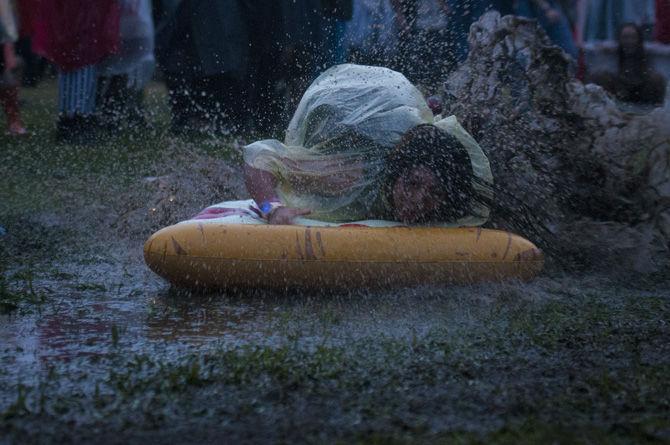 A festivalgoer slides through a muddy puddle on an inflatable pizza on Saturday, Oct. 31, 2015, during the annual Voodoo Music + Arts Experience at City Park in New Orleans.