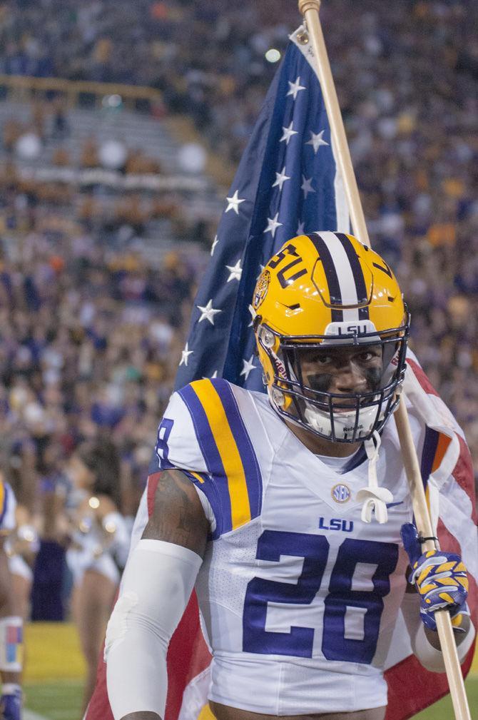 LSU senior safety Jalen Mills (28) walks onto the field with the American flag during the Tigers' 31-14 defeat against the University of Arkansas on Nov. 14. 2015 in Tiger Stadium.