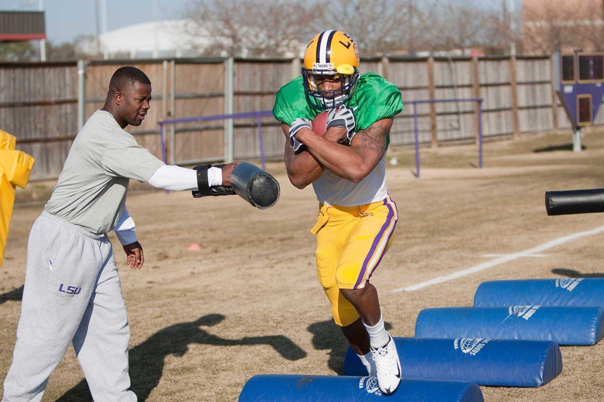 Former LSU running back Richard Murphy, right, runs a drill at practice March 4, 2010, while running backs coach Frank Wilson tries to knock the ball away.