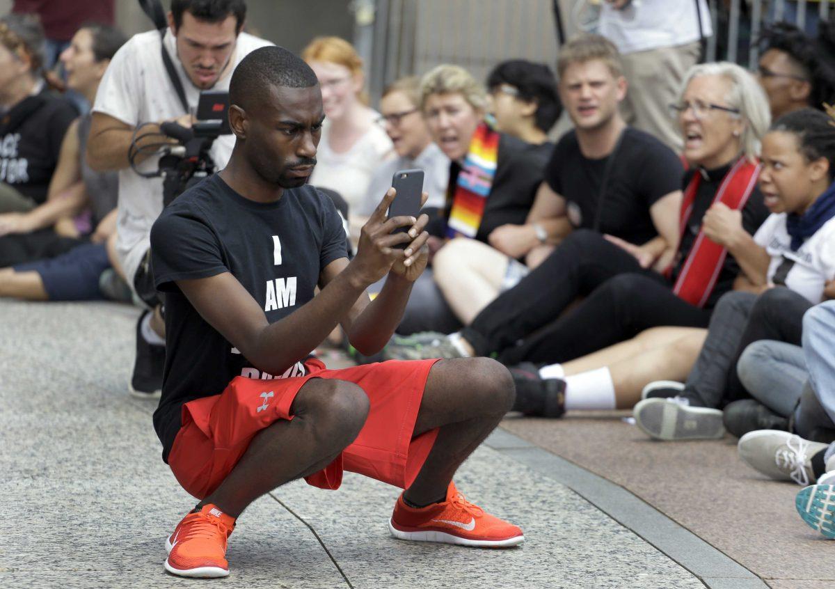 FILE - In an Aug. 10, 2015 file photo, protester and social media activist DeRay McKesson records outside the Thomas F. Eagleton Federal Courthouse Monday, in St. Louis. Mckesson has joined the crowded 2016 Baltimore mayoral race. Maryland's State Board of Elections shows that he filed Wednesday, Jan. 3, 2016, to run in the Democratic primary along with 12 other candidates. (AP Photo/Jeff Roberson, File)