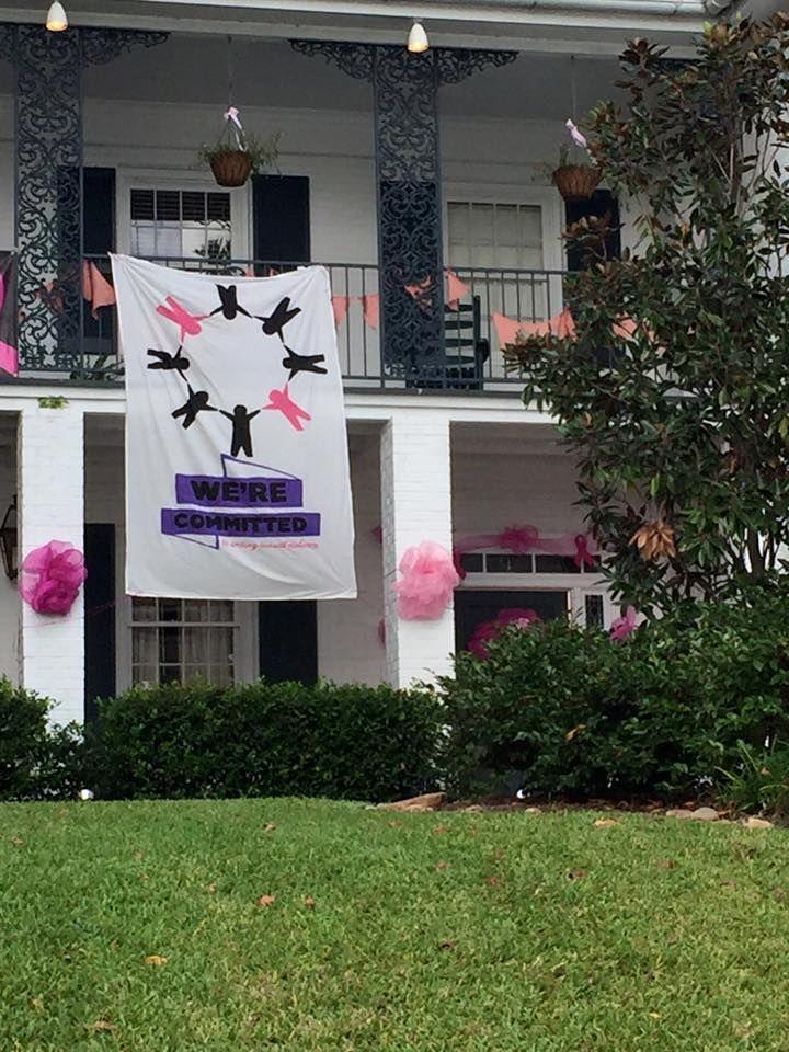 A banner for the We're Committed campaign hangs from the balcony of the Zeta Tau Alpha sorority house.