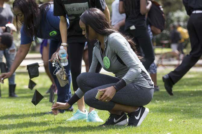 Participants place black flags in the ground to remember the 117 black lives that were lost to police brutality so far in 2016 on Monday, February 29, 2016 at the Parade Ground.