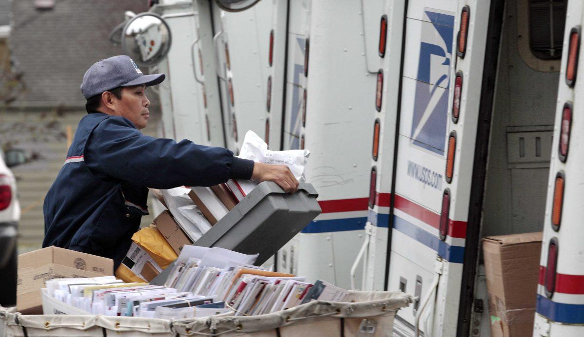 FILE - This Dec. 5, 2011 file photo shows letter carrier Diosdado Gabnat moving boxes of mail into his truck to begin delivery at a post office in Seattle. Americans for generations have come to depend on door-to-door mail delivery. It&#8217;s about as American as apple pie. But with the Postal Service facing billions of dollars in annual losses, the long-cherished delivery service could be virtually phased-out by 2022 under a proposal a House panel was considering Wednesday. Curbside delivery, which includes deliveries to mailboxes at the end of driveways, and cluster box delivery would replace letter carriers slipping mail into front-door boxes. (AP Photo/Elaine Thompson, File)