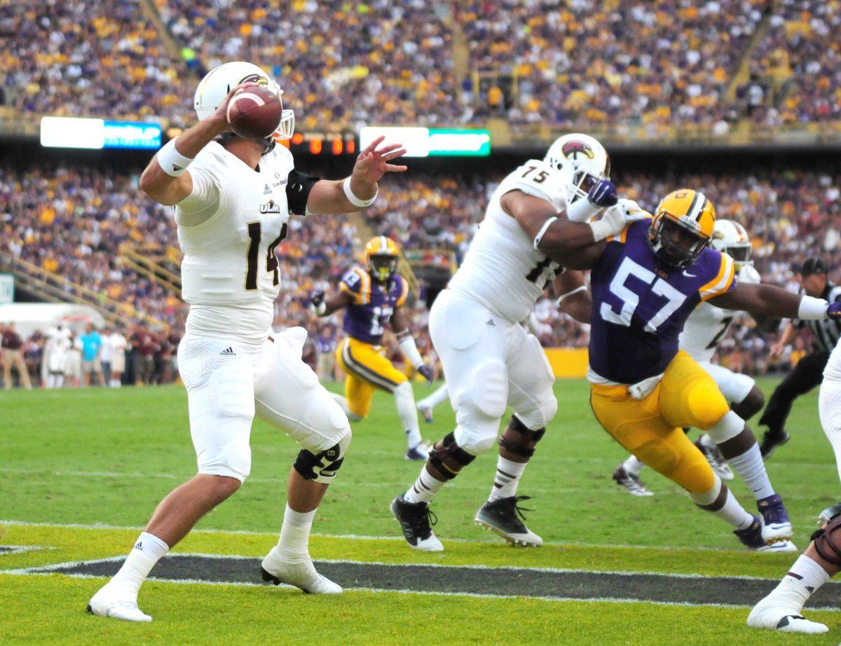 LSU freshman defensive tackle Davon Godchaux (57) lunges toward ULM senior quarterback Pete Thomas (14) Saturday, Sep. 13, 2014 during the Tigers' 31-0 victory against the Warhawks in Tiger Stadium.