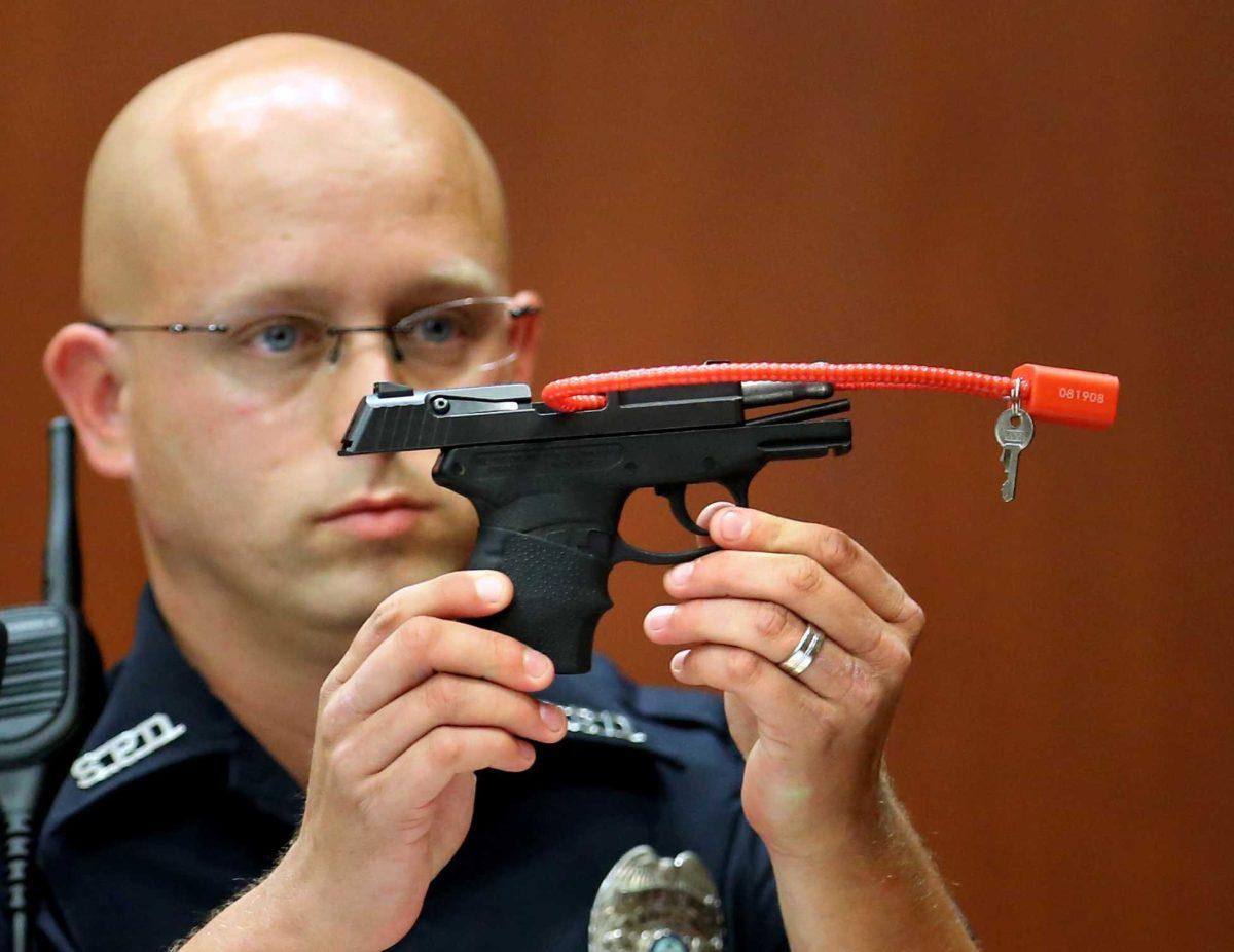 FILE- In this June 28, 2013, file photo, Sanford police officer Timothy Smith holds up the gun that was used to kill Trayvon Martin, while testifying in the George Zimmerman trial, in Seminole circuit court in Sanford, Fla. The pistol former neighborhood watch volunteer Zimmerman used in the fatal shooting of Martin is going up for auction online. (AP Photo/Orlando Sentinel, Joe Burbank, Pool, File)