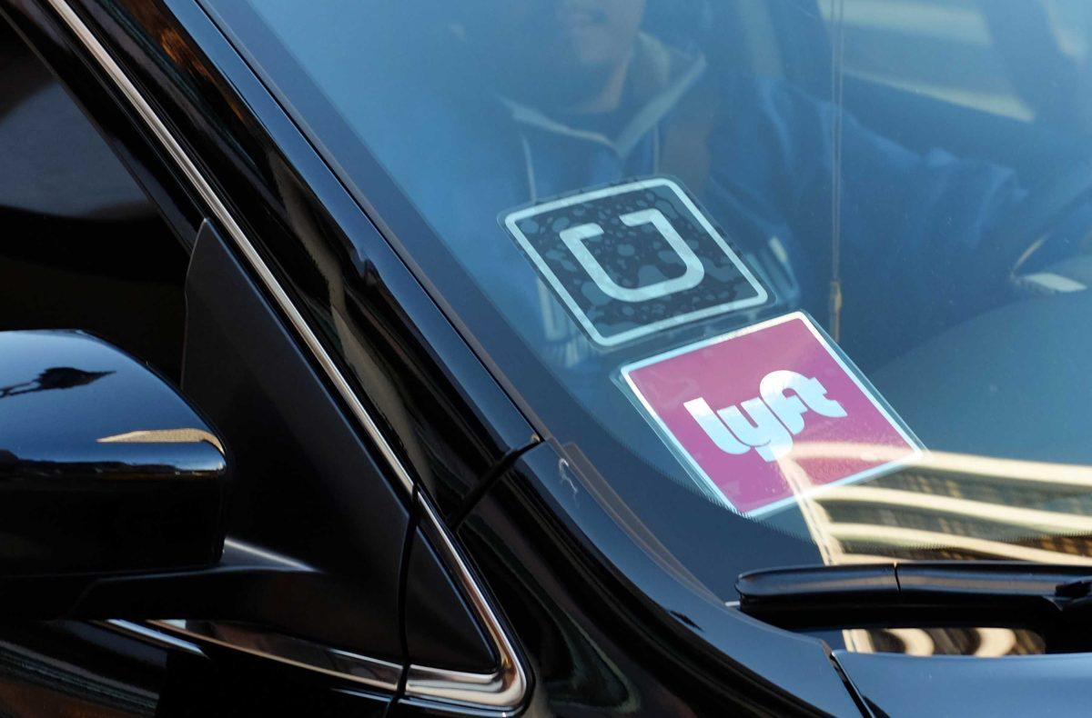 FILE - In this Tuesday, Jan. 12, 2016, file photo, a driver displaying Lyft and Uber stickers on his front windshield drops off a customer in downtown Los Angeles. Hailing a ride with a smartphone app in many U.S. cities could come down to a fight over fingerprints. Following incidents where Uber drivers were found to have criminal records, a growing number of state and local governments want ride-hailing drivers to undergo fingerprint background checks. Uber and its chief rival, Lyft, have fought those checks, contending their own method of vetting drivers is just as safe. (AP Photo/Richard Vogel, File)