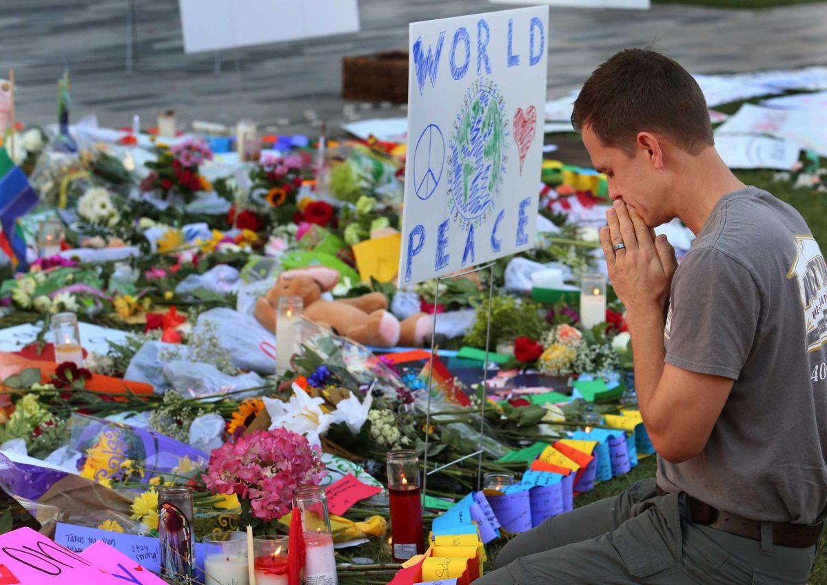 Matt Mitchell, 42, of Orlando who was born and raised in Orlando takes a moment Tuesday, June 14, 2016 to pray at a growing memorial at the The Dr. Phillips Center for the victims of the mass shooting Sunday at the Pulse Nightclub. (Red Huber/Orlando Sentinel via AP) ** LEESBURG OUT, LADY LAKE OUT , DAYTONA BEACH NEWS JOURNAL OUT , TV OUT, MAGS OUT, NO SALES **