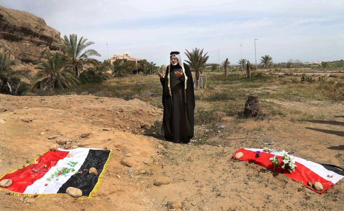 FILE - In this April 3, 2015, file photo, an Iraqi man prays for his slain relative at the site of a mass grave believed to contain the bodies of Iraqi soldiers killed by Islamic State group militants when they overran Camp Speicher military base in Tikrit, Iraq, in June 2014. An analysis by The Associated Press has found 72 mass graves left behind by Islamic State extremists in Iraq and Syria, and many more are expected to be discovered as the group loses territory. (AP Photo/Khalid Mohammed, File)