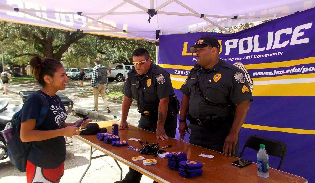 Angelita Campos, kinesiology senior from Opelousas, learns about the benefits of the mobile LSU Shield app from LSU Police Officer Jared Hebert and Sgt. David West.&#160;