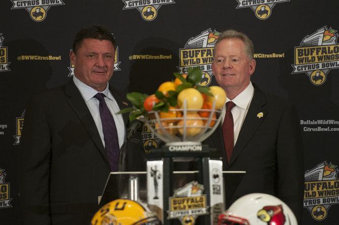 LSU coach Ed Orgeron shakes hands with Louisville head coach Bobby Petrino on Friday, Dec. 30, 2016, during a Buffalo Wild Wings Citrus Bowl press conference at the Hilton Hotel in Orlando.