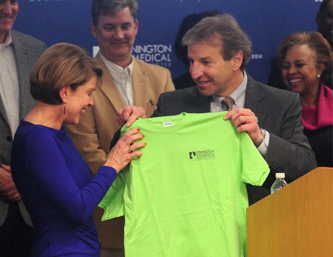 <p>Paula Pennington de la Bretonne receives an honorary shirt from Pennington Biomedical Research Center executive director William T. Cefalu on Wednesday, Jan. 22, 2014 at the Translational Research Clinic for Children.</p>