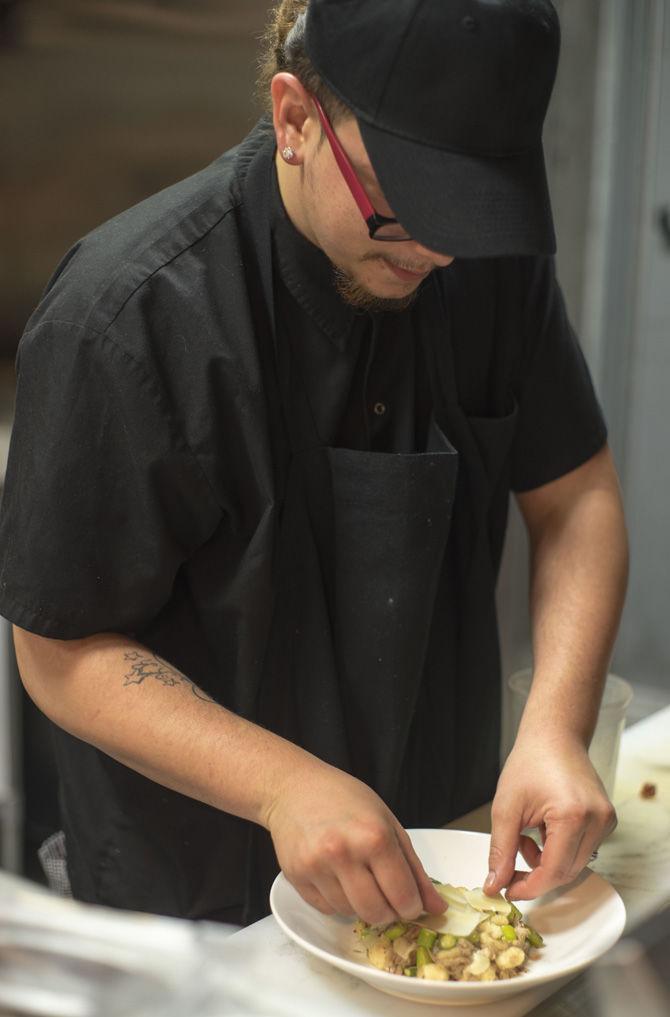 A cook garnishes a dish at Cocha on Feb. 20, 2017.