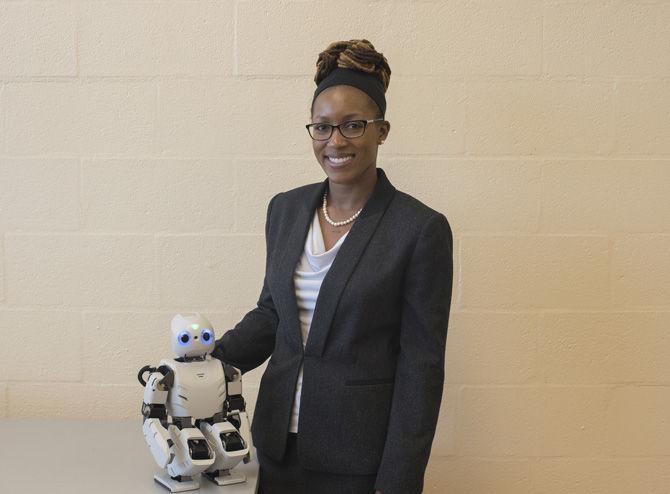 Assistant Professor LaVonda Brown rests her hand on the robot Darwin on March 29, 2017 in the Electrical Engineering Building.