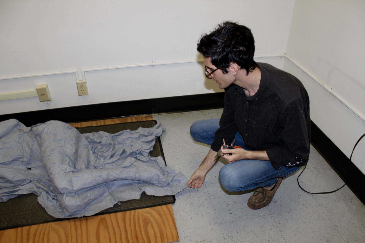 Photography senior James Letten shows a sculpture made of paper of his own body.