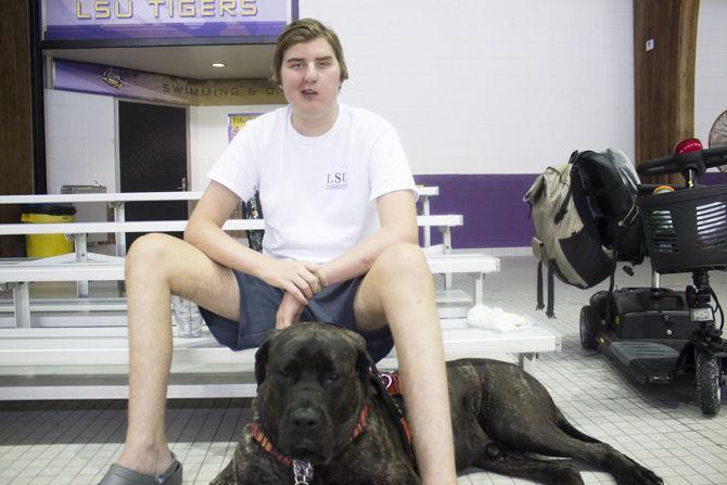 LSU swim team manager Kayne Finley sits with his service dog in the Natatorium, on Wednesday Oct. 4, 2017.