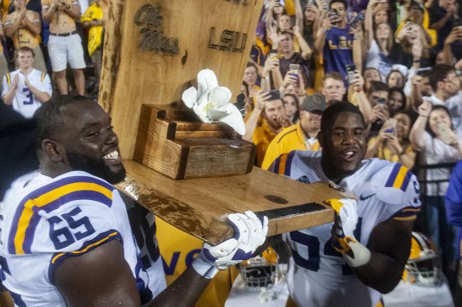 LSU freshman defensive tackle Davin Cotton (54) and sophomore offensive line Jakori Savage (65) hold up the Magnolia Bowl trophy during the Tigers&#8217; 45-16 victory over Ole Miss on Saturday Sept. 29, 2018, in Tiger Stadium.