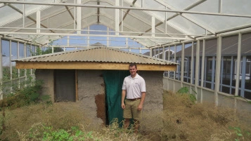 Assistant Professor of Entymology Daniel Swale stands in front of a semi-field habitat used for studying the horizontal transfer of novel K+ channel insecticides.