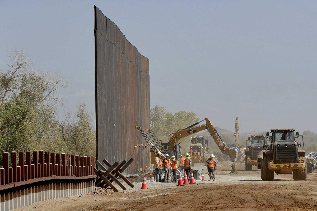 Government contractors erect a section of Pentagon-funded border wall along the Colorado River, Tuesday, Sept. 10, 2019 in Yuma, Ariz. The 30-foot high wall replaces a five-mile section of Normandy barrier and post-n-beam fencing, shown at left, along the the International border that separates Mexico and the United States. Construction began as federal officials revealed a list of Defense Department projects to be cut to pay for President Donald Trump's wall. (AP Photo/Matt York)