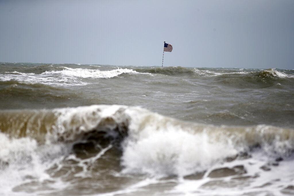 Waves crash in front of an American flag in advance of the potential arrival of Hurricane Dorian, in Vero Beach, Fla., Monday, Sept. 2, 2019.&#160;