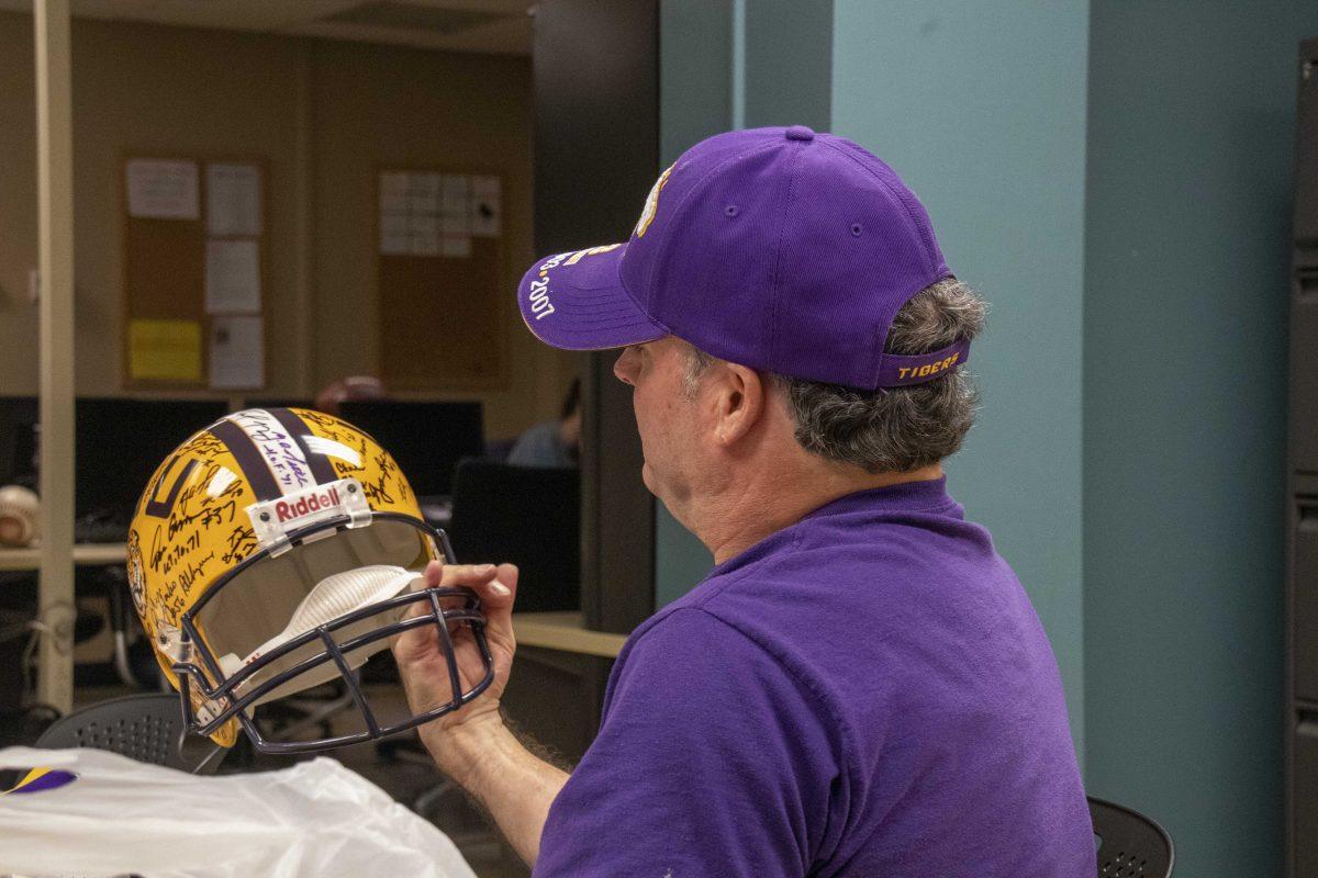 David Haynes gazes upon a helmet signed by many players of LSU's past in the Reveille News Room in Hodges Hall on Tuesday, Nov. 19, 2019.