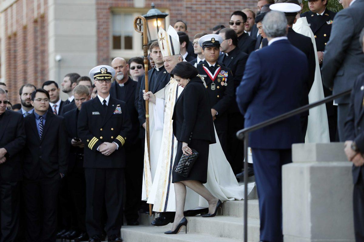 FILE - In this March 21, 2018, file photo, Gayle Benson, widow of NFL New Orleans Saints and NBA New Orleans Pelicans owner Tom Benson, walks down the steps to receive his casket with New Orleans Archbishop Gregory Aymond for visitation at Notre Dame Seminary in New Orleans. Attorneys for several men suing the Roman Catholic church say documents they obtained through discovery show that the New Orleans Saints team aided the Archdiocese of New Orleans in its &#8220;pattern and practice of concealing its crimes.&#8221; (AP Photo/Gerald Herbert, File)