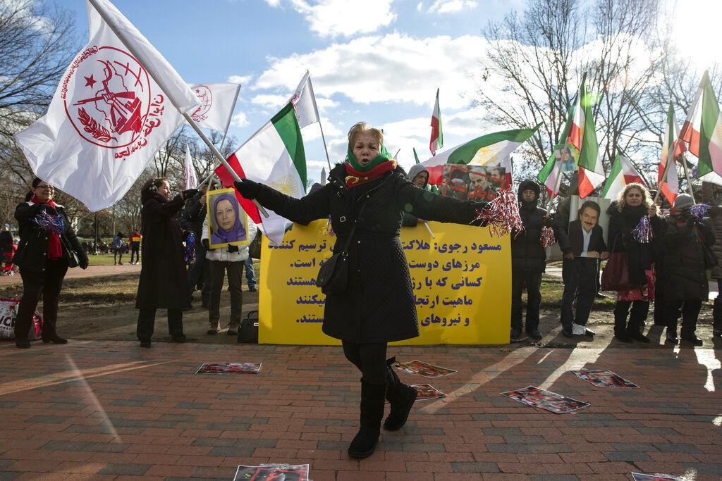 A supporters of the Mujahedeen-e-Khalq, or the MEK, an Iranian exile group, dances as others hold signs and flags during a show of support for a U.S. airstrike in Iraq that killed Iranian Gen. Qassem Soleimani, in Lafayette Park across from the White House, Sunday, Jan. 5, 2020, in Washington. (AP Photo/Alex Brandon)