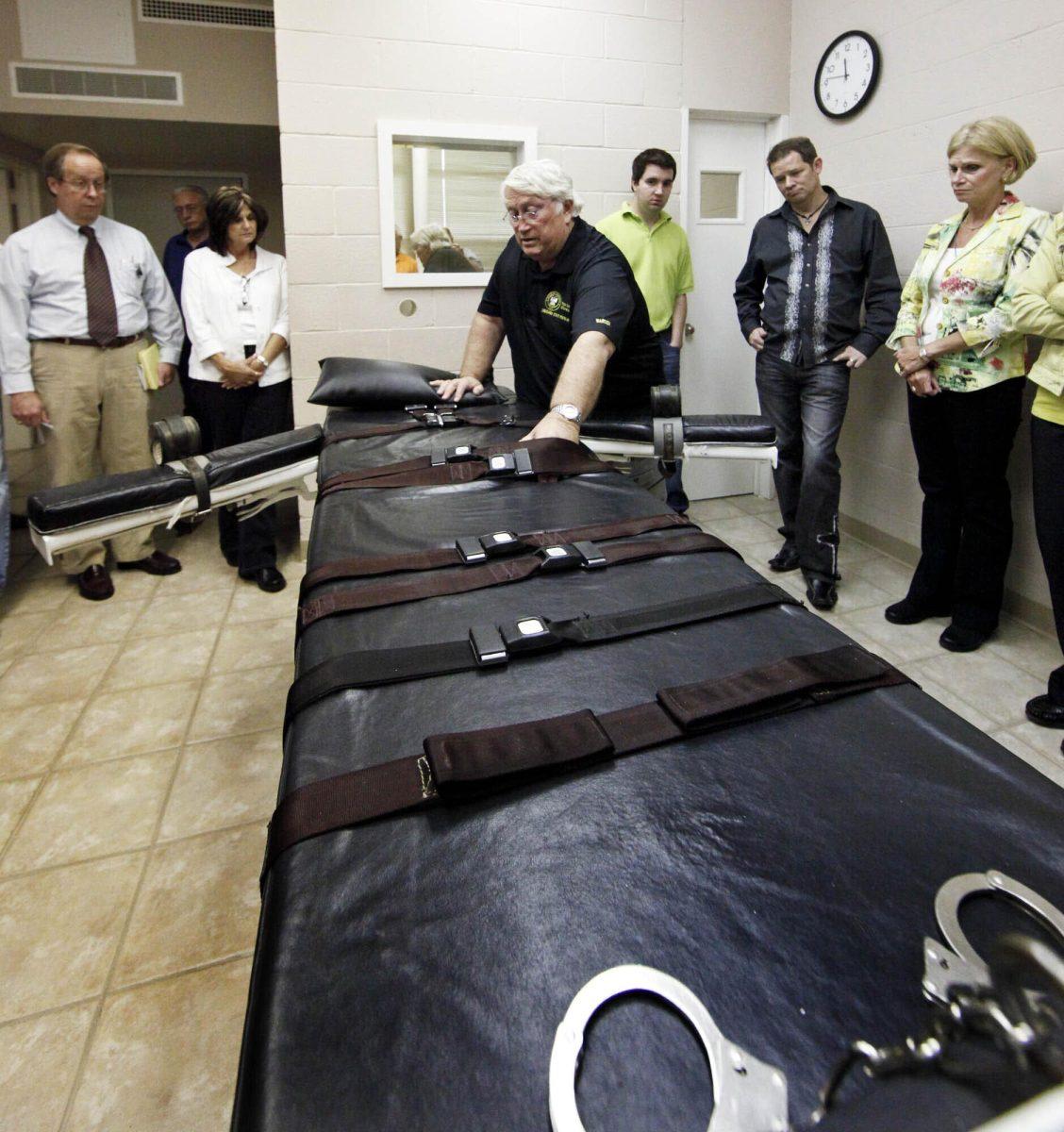 FILE - In this Sept. 18, 2009, file photo, Warden of the Louisiana State Penitentiary, Burl Cain, discusses the gurney used for lethal injections to Ruth Graham, far right and others as they visit the Louisiana State Penitentiary in Angola, La. Louisiana cleans its execution chamber at the state penitentiary daily, but it's been more than a decade since a condemned prisoner has laid on the chamber's black-padded gurney to die. Sixty-eight people sit on Louisiana&#8217;s death row, with no execution dates set. Though the state historically has been tough on crime and holds the dubious distinction as the nation's incarceration capital, Louisiana seems to be doing very little to carry out its death penalty. (AP Photo/Judi Bottoni, File)