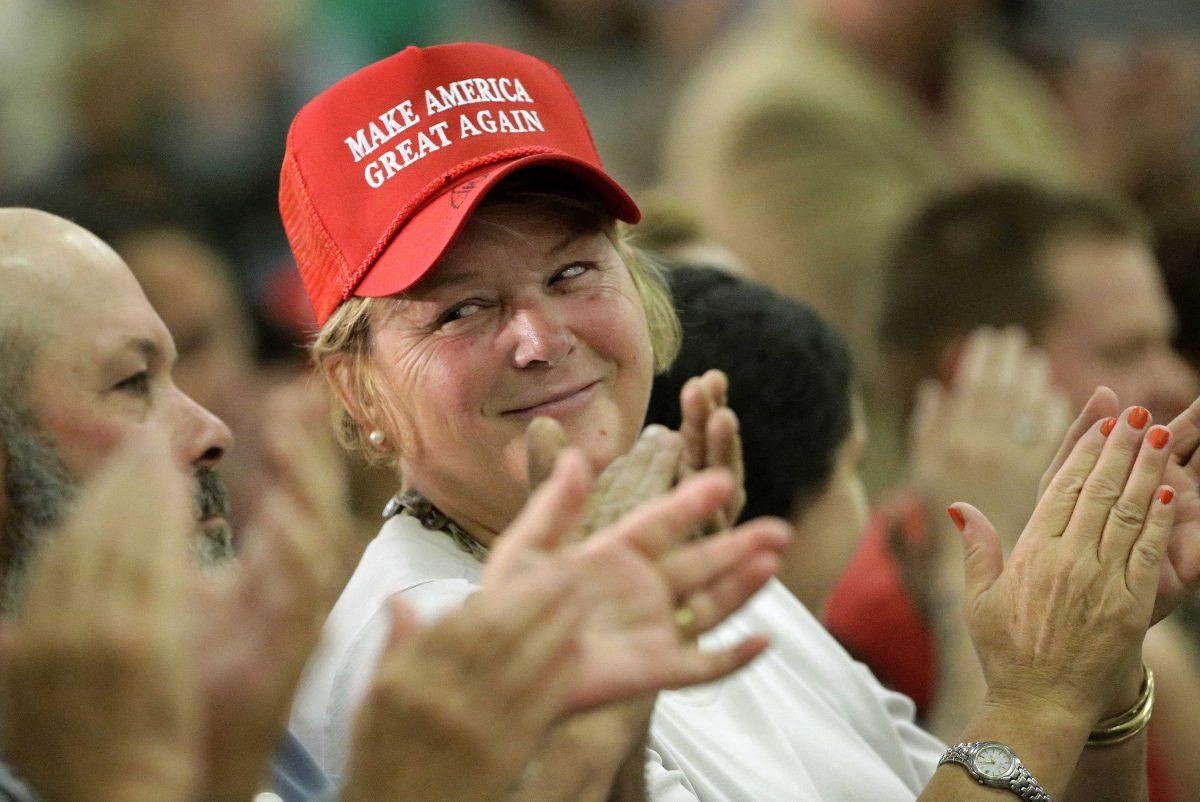 A woman wearing a Donald Trump presidential campaign hat applauds during a campaign stop for the Republican candidate, Wednesday, Sept. 30, 2015, in Keene, N.H. (AP Photo/Steven Senne)