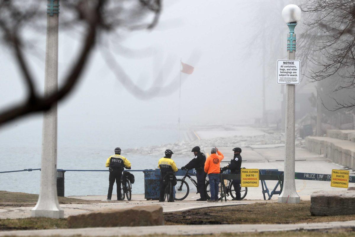 Members of the Chicago Police Department's bicycle patrol wait in the fog at a barricade where a trail along Lake Michigan was closed to all traffic, Thursday, March 26, 2020, in Chicago. (AP Photo/Charles Rex Arbogast)