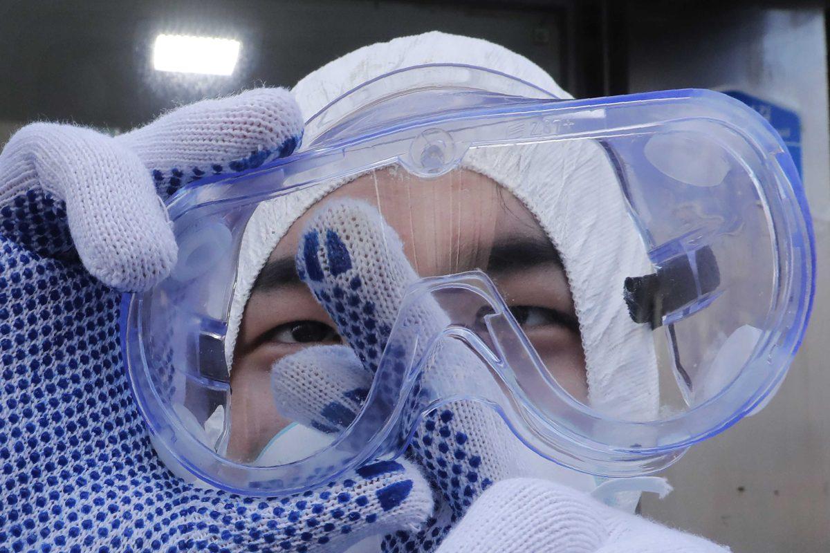 A worker cleans his goggles to spray disinfectant as a precaution against the coronavirus at a shopping street in Seoul, South Korea, Feb. 27, 2020. (AP Photo/Ahn Young-joon)