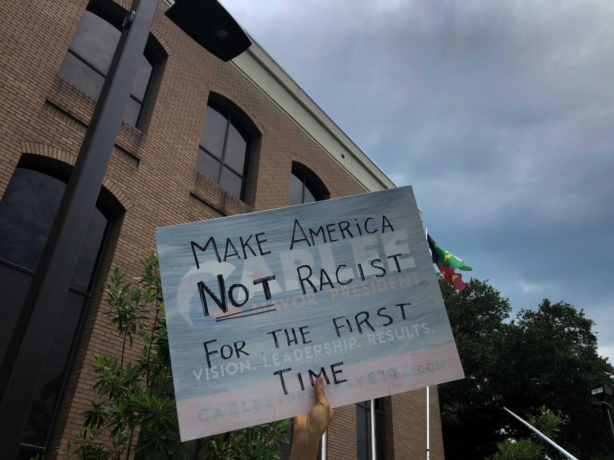 Outside the Lafayette Police Station on University Ave., a protestor holds a sign that reads "Make America not racist for the first time."