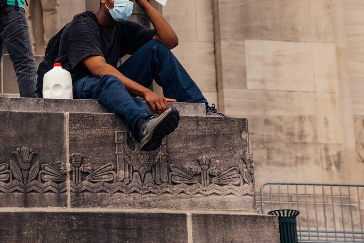 A protester sits with a gallon of milk on Sunday, May 31, 2020 during the protest of the death of George Floyd at the State Capitol in Downtown Baton Rouge.