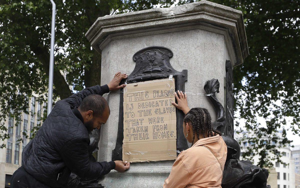 A banner is taped over the inscription on the pedestal of the toppled statue of Edward Colston in Bristol, England, Monday, June 8, 2020. The toppling of the statue was greeted with joyous scenes, recognition of the fact that he was a notorious slave trader &#8212; a badge of shame in what is one of Britain&#8217;s most liberal cities. (AP Photo/Kirsty Wigglesworth)